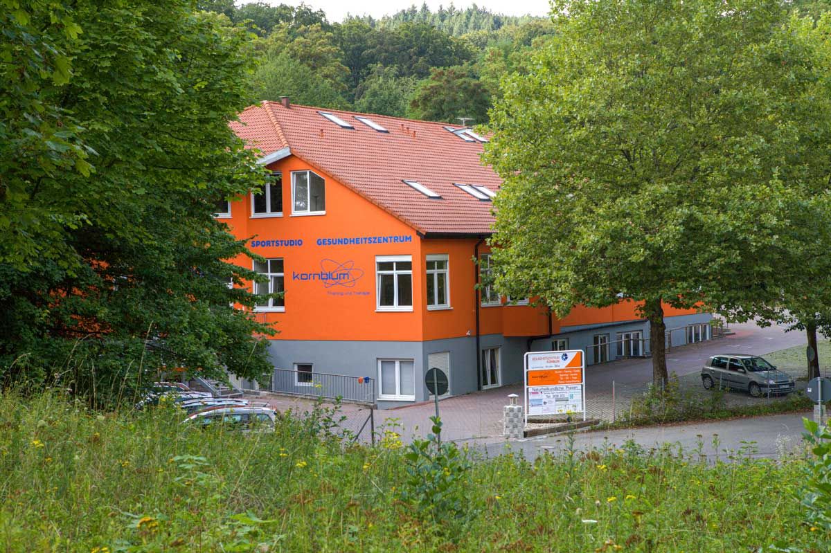 Das Gebäude des Gesundheitszentrums Kornblum mit der Aufschrift Sportstudio und Gesundheitszentrum, umgeben von Bäumen